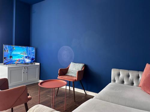 a living room with blue walls and a couch and chairs at PROMO Elegant Apartments NEW - Colorful by the sea in Durrës