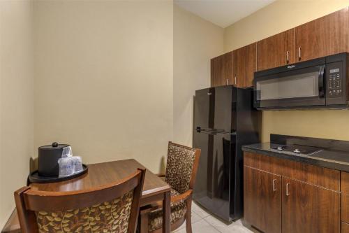 a kitchen with a table and a black refrigerator at Best Western Plus Hudson Hotel & Suites in Hudson
