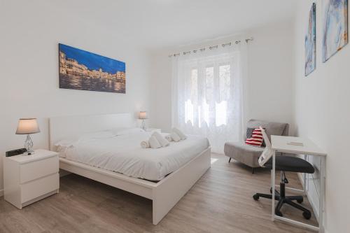 a white bedroom with a bed and a desk and a chair at Burlo Garofalo Elegant Apartment Near Hospital in Trieste