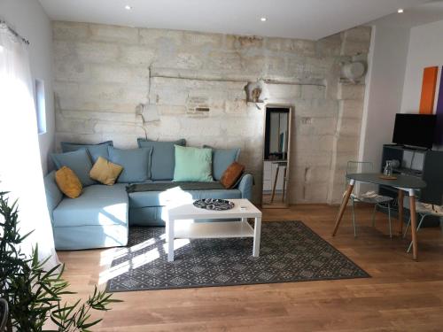 Una sala de estar con un sofá azul y una mesa. en Nomad's house - 2G, en Aviñón
