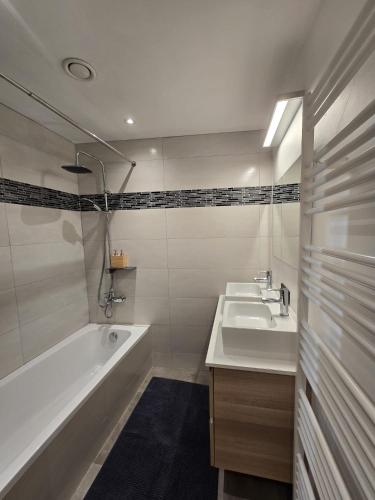 a white bathroom with two sinks and a bath tub at Chambre 2 P à Saint Hubert in Saint-Hubert