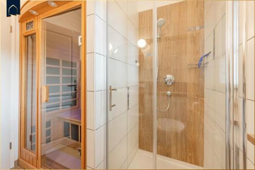 a shower with a glass door in a bathroom at Waldsiedlung DHH Waldhaus 5 in Korswandt
