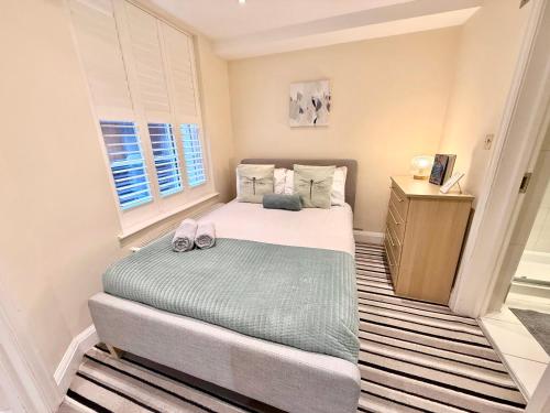 a small bedroom with a bed and a wooden cabinet at 3-Bedroom Apartment with private Terrace in Pimlico, Westminster & Victoria by Staylio London in London
