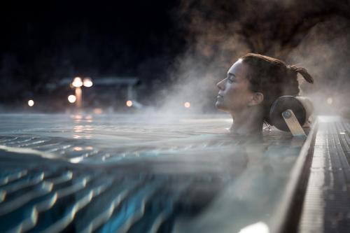 a woman swimming in a swimming pool at night at Ferienwohnungen Haid in Oetz
