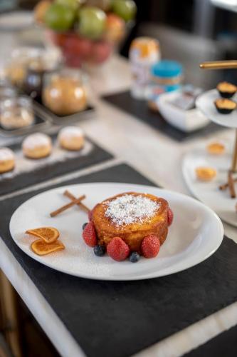 een wit bord met een stuk taart en bessen op een aanrecht bij Condes de Azevedo Palace Apartments in Porto