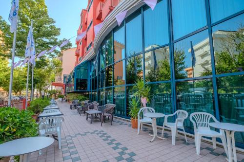 eine Reihe von Tischen und Stühlen vor einem Gebäude in der Unterkunft Family Hotel Mediterraneo - Azzurro Club in Cesenatico