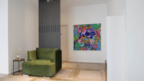 a green chair in a room with a painting at Corte Novella Hotel & Residence in Brescia