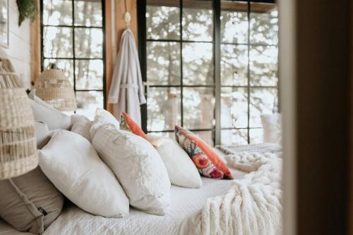 a bed with white pillows on it with windows at The Water’s Edge * * Unique Muskoka Treehouse * * in Windermere