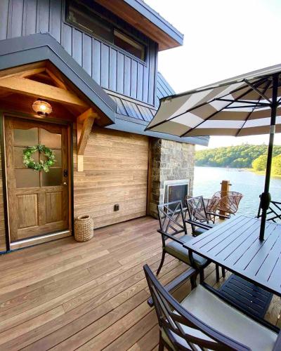 a wooden deck with a table with chairs and an umbrella at The Water’s Edge * * Unique Muskoka Treehouse * * in Windermere
