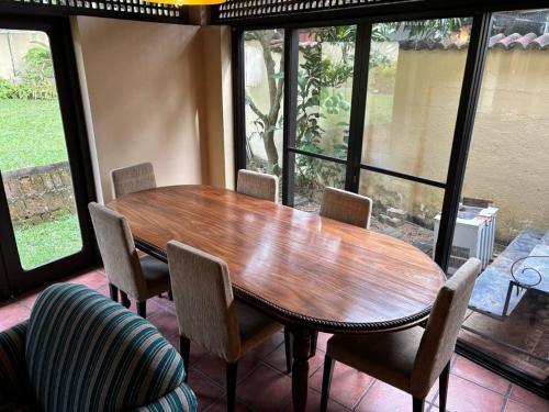 a wooden table and chairs in a room with windows at 19 St Stephen's in Sri Jayewardenepura Kotte
