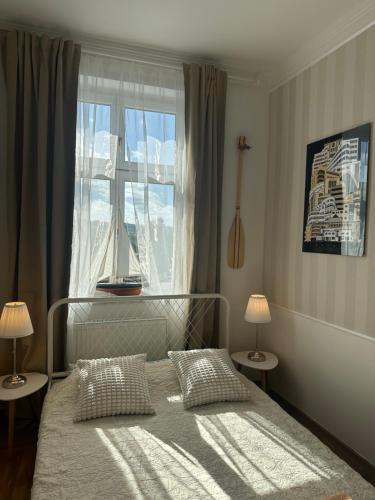 a bedroom with a bed with two lamps and a window at Happy8 in Gdynia