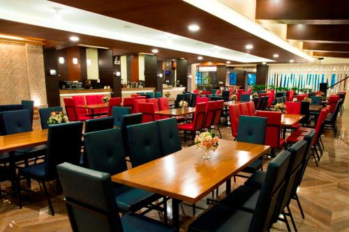 um restaurante com mesas e cadeiras de madeira e cadeiras vermelhas em Venus Parkview Hotel em Baguio