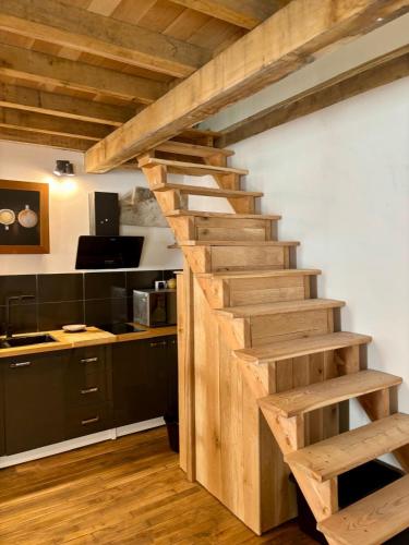un escalier en bois dans une cuisine avec des armoires noires dans l'établissement Au cœur de la Citadelle, à Semur-en-Auxois