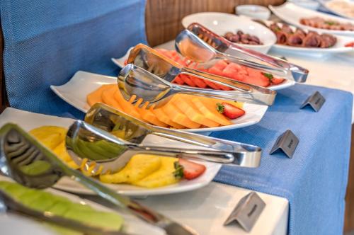a table topped with plates of fruit and tongs at City Lodge Hotel Waterfall City in Midrand