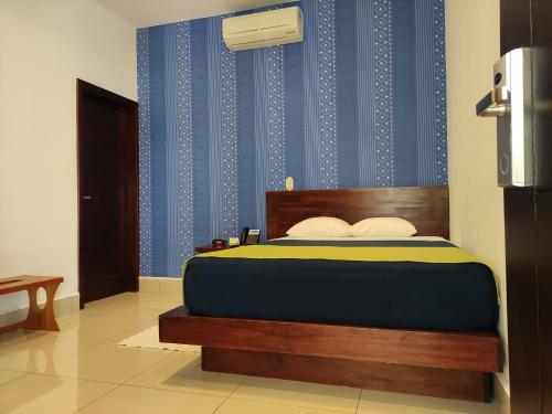 a bedroom with a bed with a blue wall at Hotel Agualcas in Managua