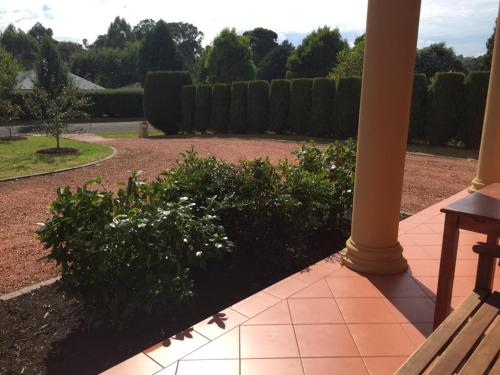a porch with a bench next to a garden at Stately Bowral Designer Home in Bowral