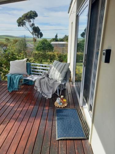 a rocking chair on a deck with a view of the ocean at 2 on Fifth Avenue in Botrivier