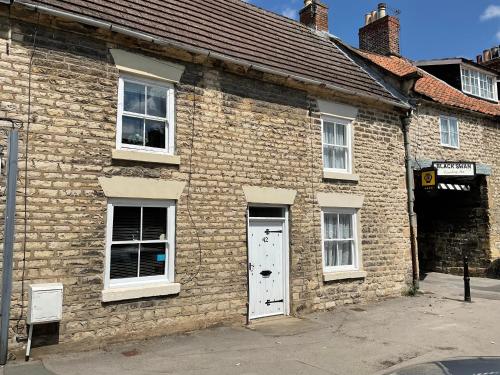 an old brick building with a white door and windows at Lark Cottage in Pickering