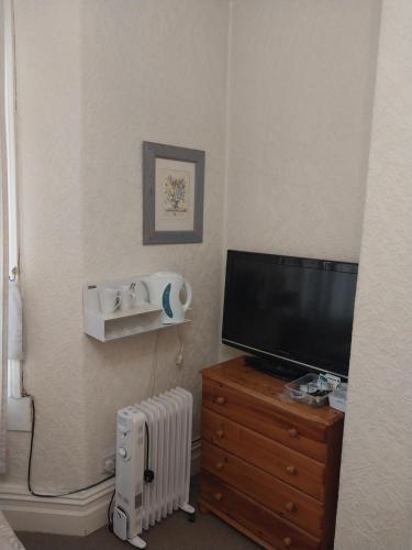 a living room with a television and a dresser with a radiator at Lynwood Hotel & Spa in Blackpool