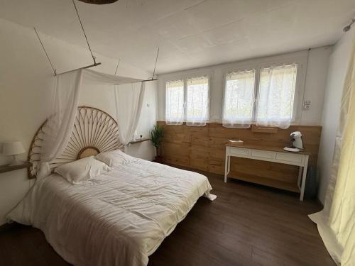 a bedroom with a large white bed and windows at La Terrasse in Argenton lʼÉglise