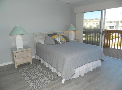 a bedroom with a bed with two lamps and a balcony at Dunes reach 2 in Dewey Beach