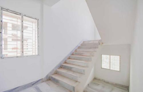 a staircase in a white room with a window at Hotel O Amar Raj Stay in Kolkata