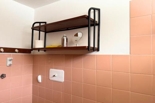 コスキンにあるCasa en Cosquínのピンクのタイルと壁に棚が付いたバスルーム