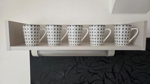 a shelf with four white cups on it at Vila Anna - Apartmány in Česká Lípa