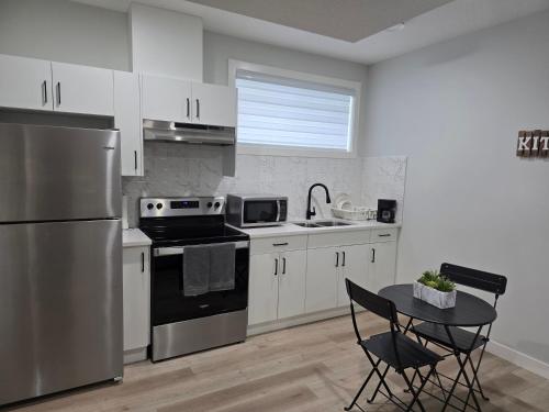 a kitchen with a stainless steel refrigerator and a table at Cozy Up in Edmonton