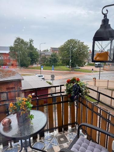 a balcony with a table and flowers on a fence at Vibrant Downtown Studio Oasis in Liepāja