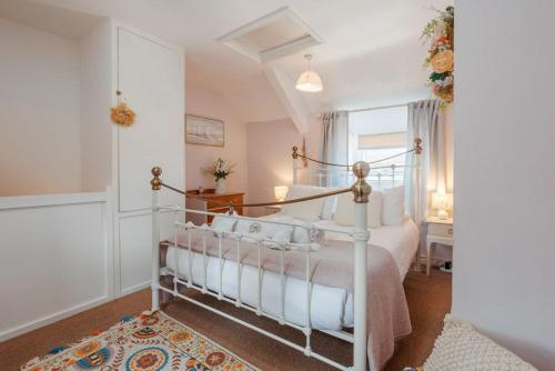 a bedroom with a white bed and a window at Angel Cottage in Swanage