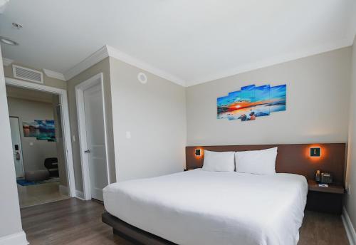 a bedroom with a white bed and a painting on the wall at Nuvo Suites Hotel - Miami Doral in Miami