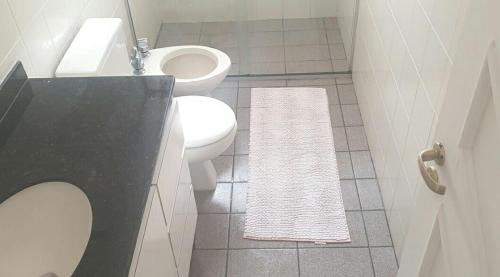a bathroom with a white toilet and a white rug at casa com piscina da edi fontes in Guarujá