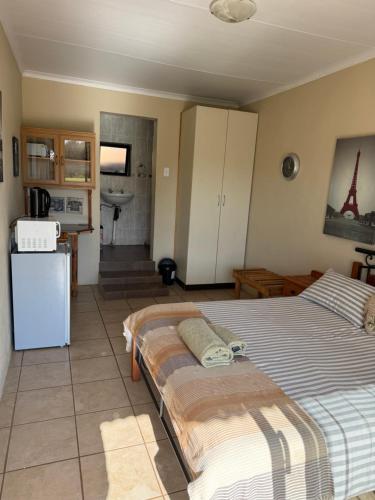 a bedroom with two twin beds and a kitchen at La Ronel Guest Farm in Roossenekal