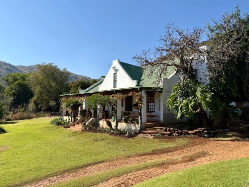 a white house with a green roof and a yard at La Ronel Guest Farm in Roossenekal