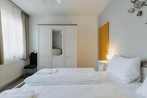una camera da letto con un letto bianco e una sedia di Apartment Zentral a Bad Tatzmannsdorf