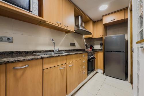 a kitchen with wooden cabinets and a stainless steel refrigerator at Casa en Barcelona in Barcelona