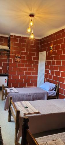 a room with two beds and a brick wall at Pousada Itatiba Holliday in Itatiba