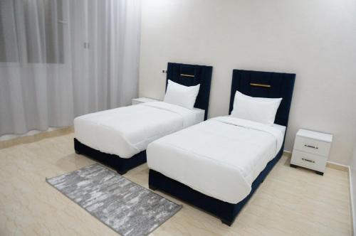 two beds in a hotel room with white sheets at 2 Voies Résidence in Dakhla