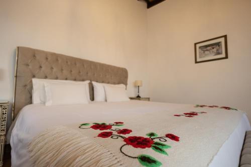 a bed with a white blanket with red flowers on it at Iraola Hotel Boutique in Cafayate