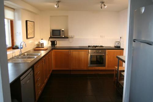 a kitchen with wooden cabinets and a sink and a microwave at Stylish 4Bed Cottage with parking near town and beach in Lyme Regis