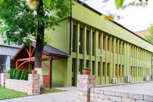 a green building with a tree in front of it at Casa TT House in Sfântu-Gheorghe