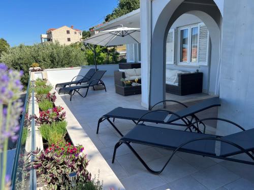 a patio with chairs and an umbrella and flowers at Apartment Infinity Blue in Mlini