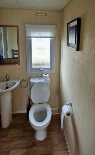 a bathroom with a toilet and a sink and a window at MOLLIES DEN 3 8 Berth 3 bedroom Waterside Leisure Park INGOLDMELLS in Ingoldmells