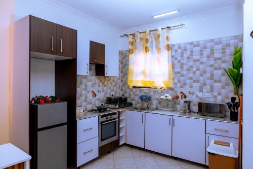 a kitchen with white cabinets and a black refrigerator at Icon Comfort Homes in Nalakonge