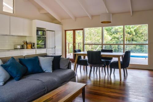 a living room with a couch and a table with chairs at Snows Creek Retreat - The Pool House in Upper Coopers Creek