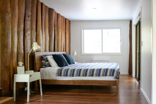 Un dormitorio con una cama con una pared de madera. en Snows Creek Retreat - The Creek House, en Upper Coopers Creek
