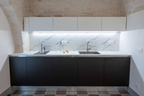 a kitchen with white cabinets and a sink at La chiave antica in Alberobello
