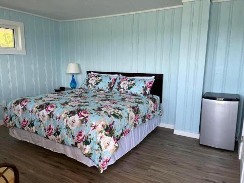 a bedroom with a bed with a floral comforter at Pete's Lakefront Motel, LLC in Geneva