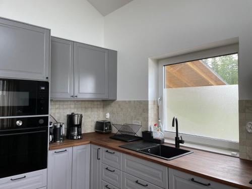 a kitchen with white cabinets and a sink and a window at Stuga i Valfjället in Åmotsfors